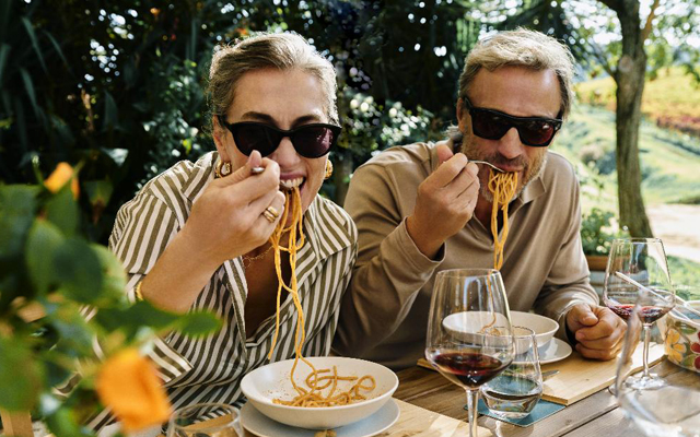 Western couple eating pasta and having wine